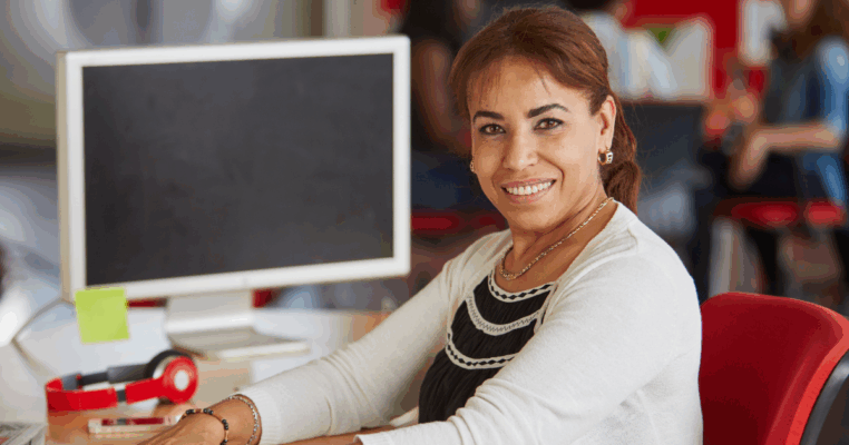 woman smiling in front of computer at desk