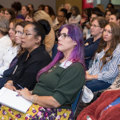 conference attendees sitting at chairs listening to presenter