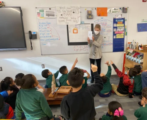 teacher showing children a paper and children pointing at it