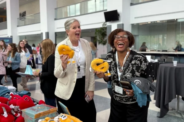 Two women smiling holding Schwa By Phonic Read-Alouds at TRL Summit